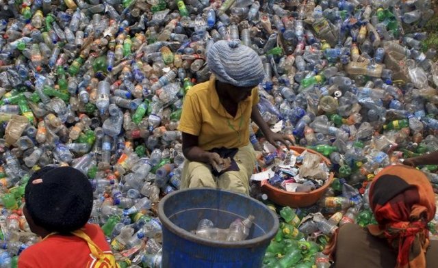 An employee of a recycling plant sorts through plastic bottles at their factory at a dumping site on the outskirts of Uganda's capital Kampala